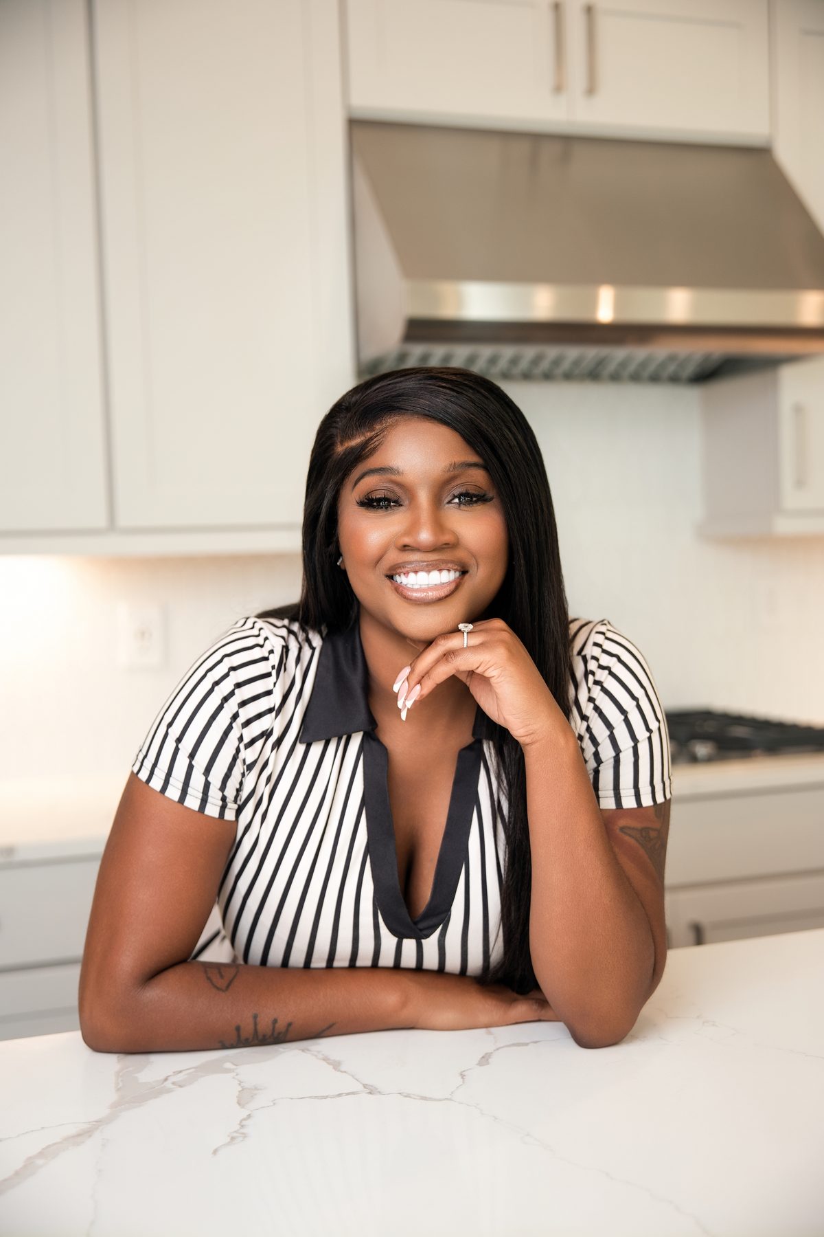 Realtor leaning on a marble counter and smiling, editorial branding portrait by ShotByJord