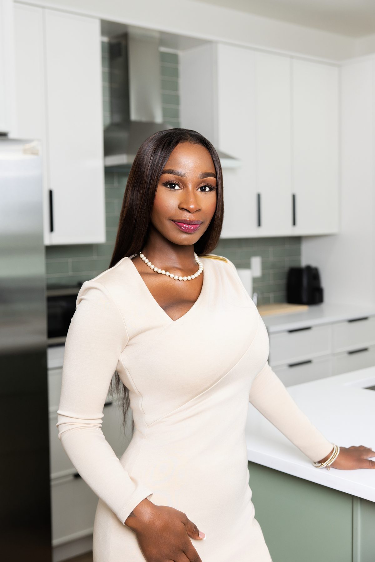 Realtor in a cream dress with a hand on the kitchen counter, personal branding portrait by ShotByJord