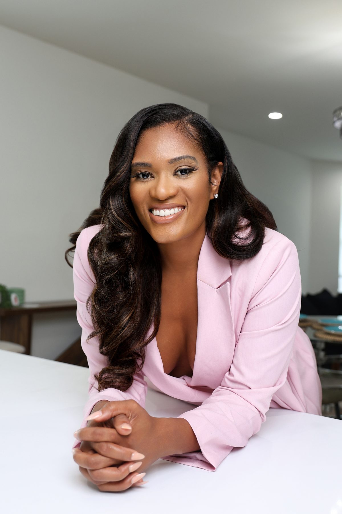 Atlanta realtor in a pink suit leaning on a counter and smiling, branding headshot by ShotByJord