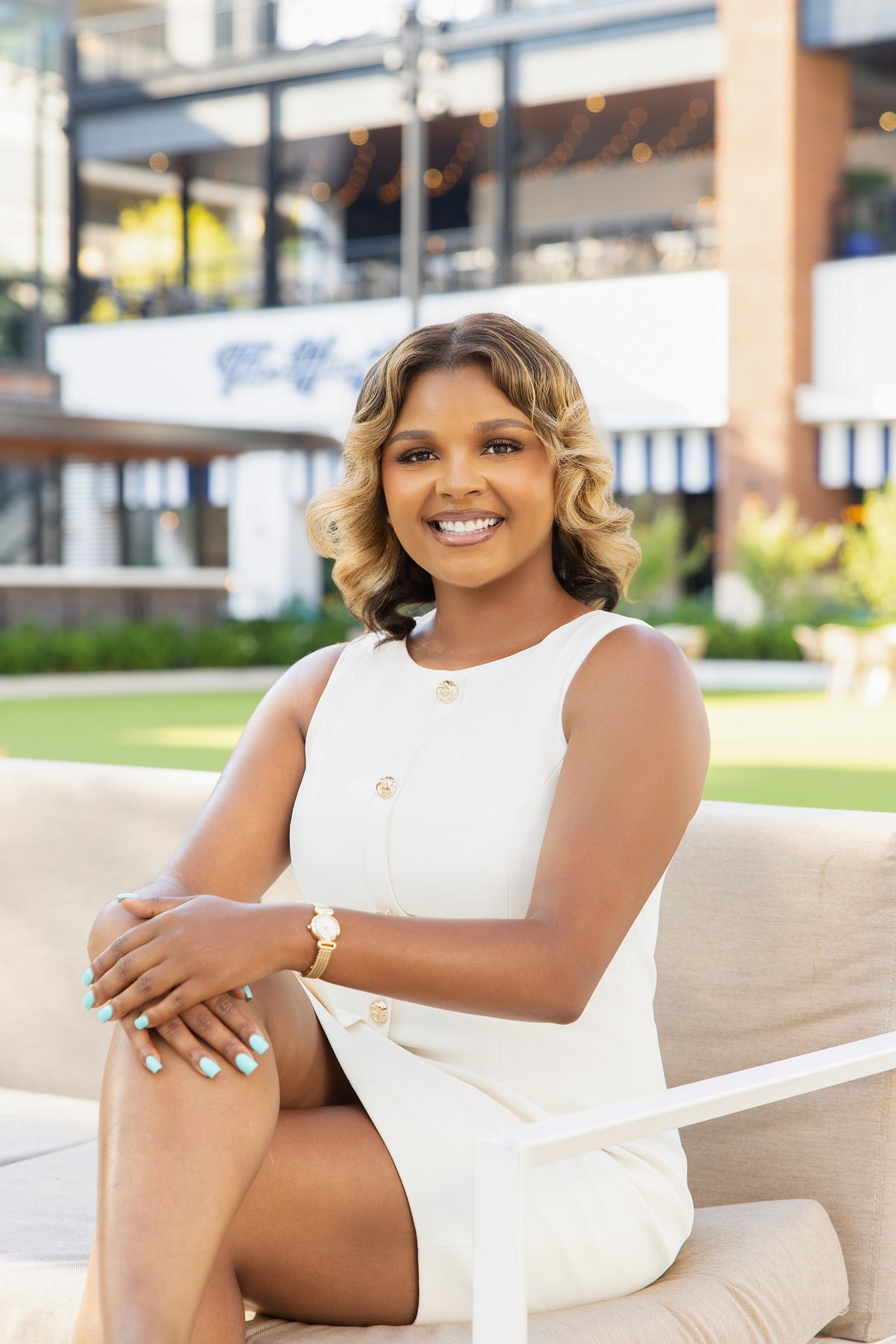 Business owner in a white dress seated on an outdoor patio sofa, personal branding portrait by ShotByJord